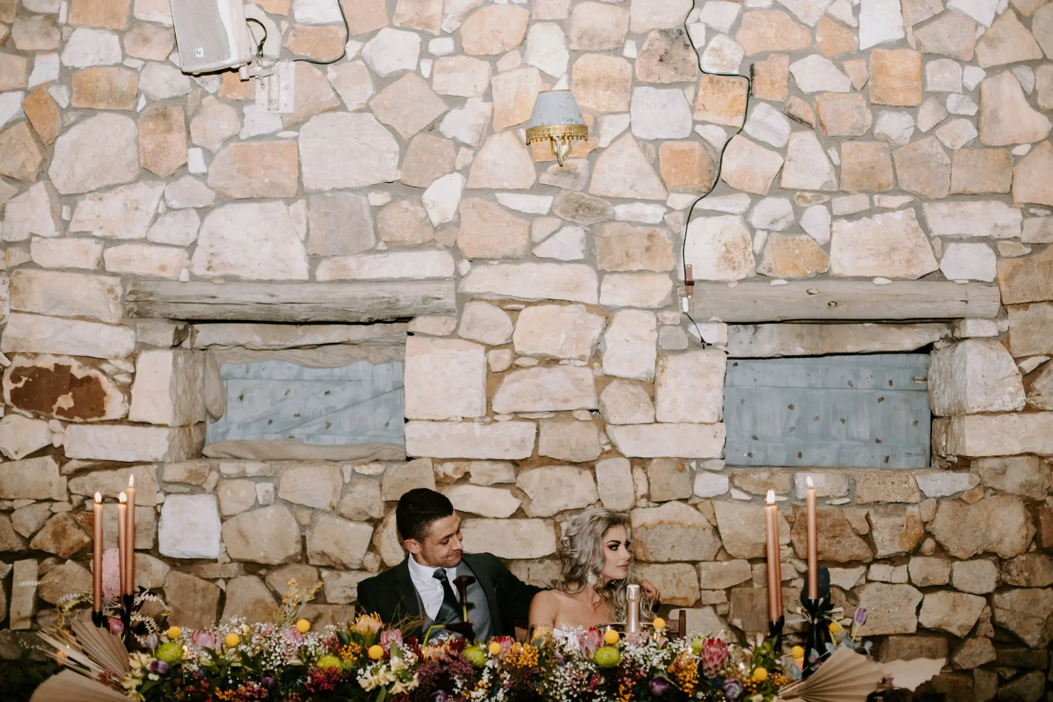A picure of Zania & Berno at a table with flowers designed by Two Balloons Weddings & Events